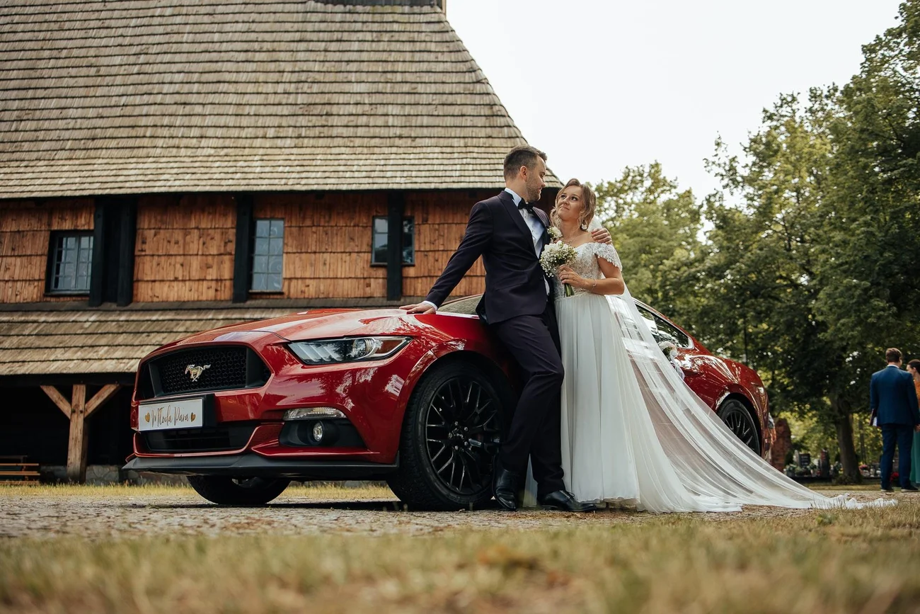Zdjęcie pary młodej z autem ślubnym