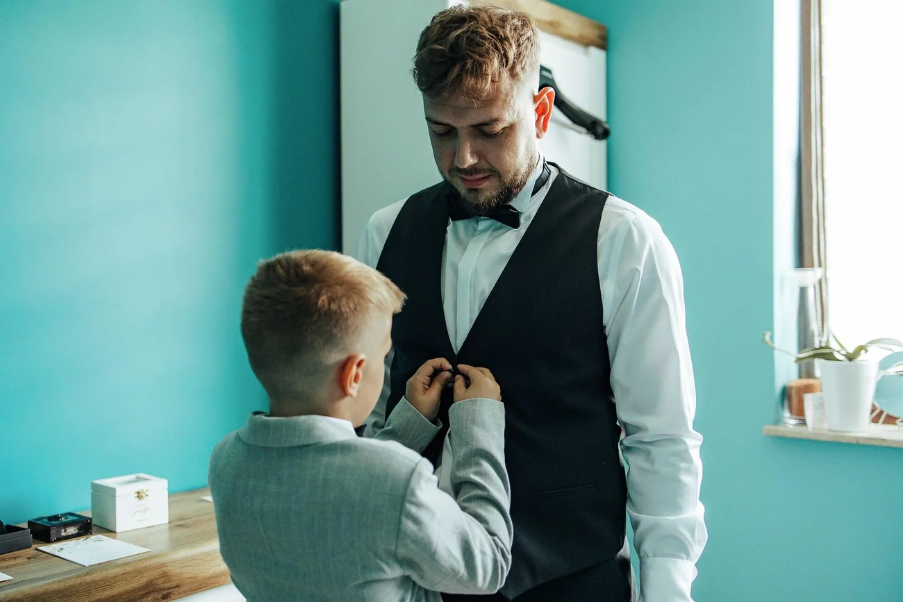 Synek zapina kamizelkę Pana Młodego - ciepły moment ojca i syna