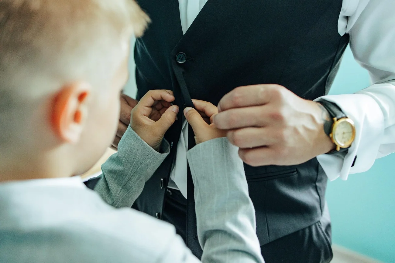 Synek pomaga Panu Młodemu zapiąć guziki marynarki - przygotowania ślubne