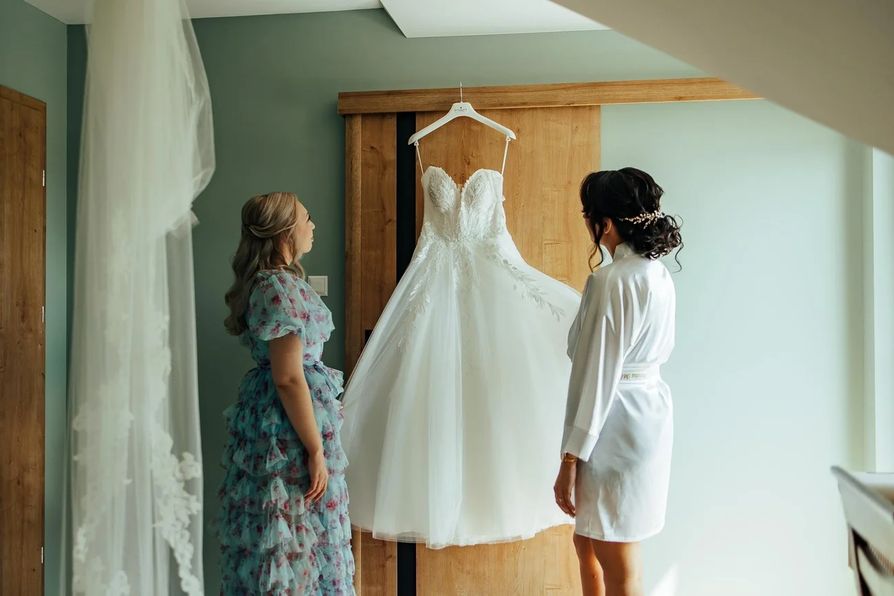 Panna Młoda z mamą oglądają suknię ślubną na wieszaku - przygotowania Sulmierzyce
